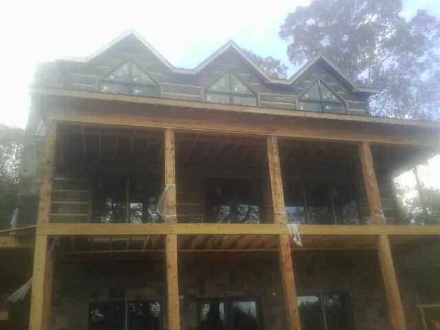 Dormers and porch framing on a large log home under construction — Roof Coating work by our crew in Blackville