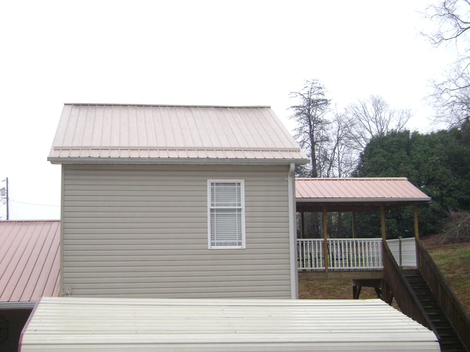 Tan metal roofs on a two story addition and attached porch, from a Roof Replacement job in Blackville