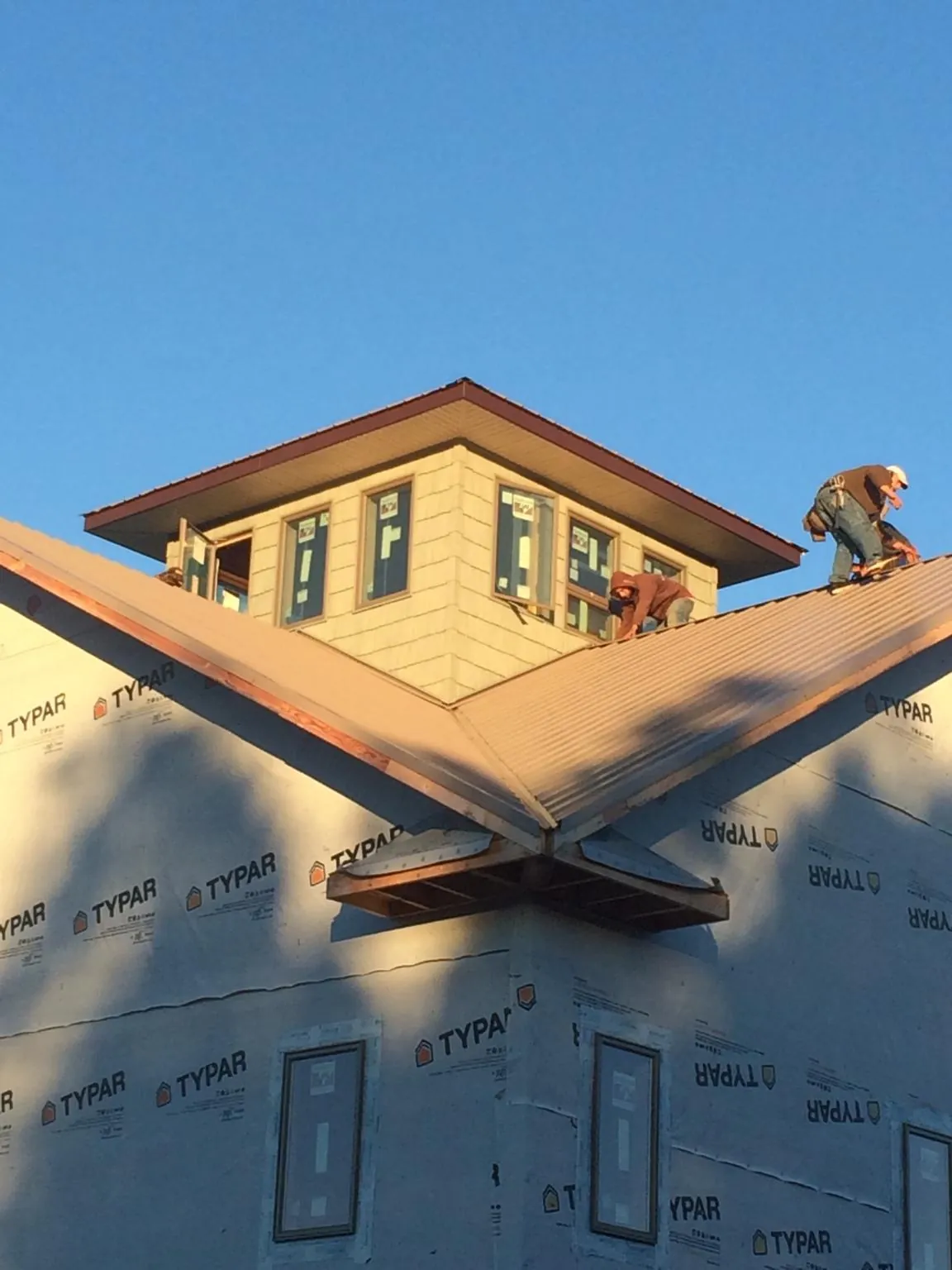 Roofers working around a rooftop cupola on a new metal roof at sunset — Roof Waterproofing in Blackville by Roofing Brothers